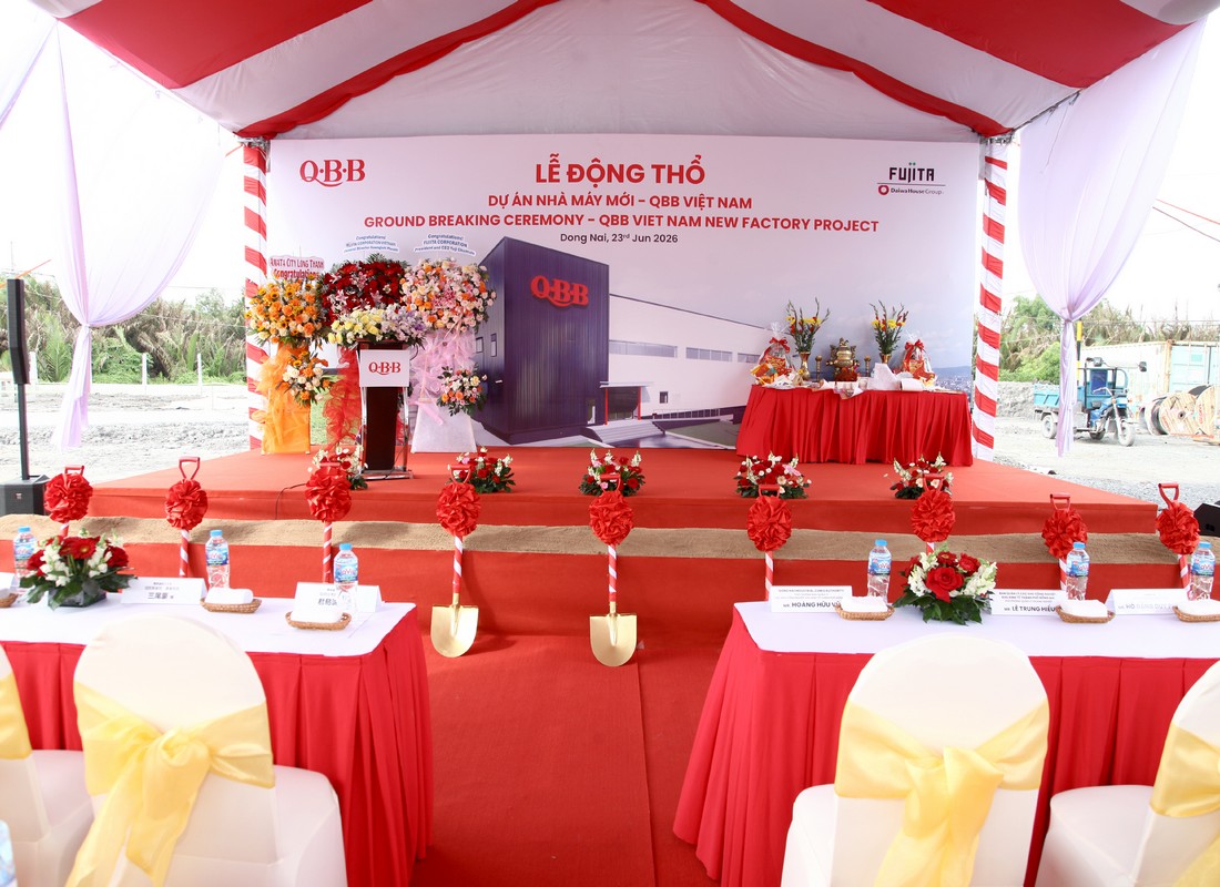 Sân khấu lễ động thổ QBB với backdrop in, bục phát biểu và khu vực xúc cát phía trước.