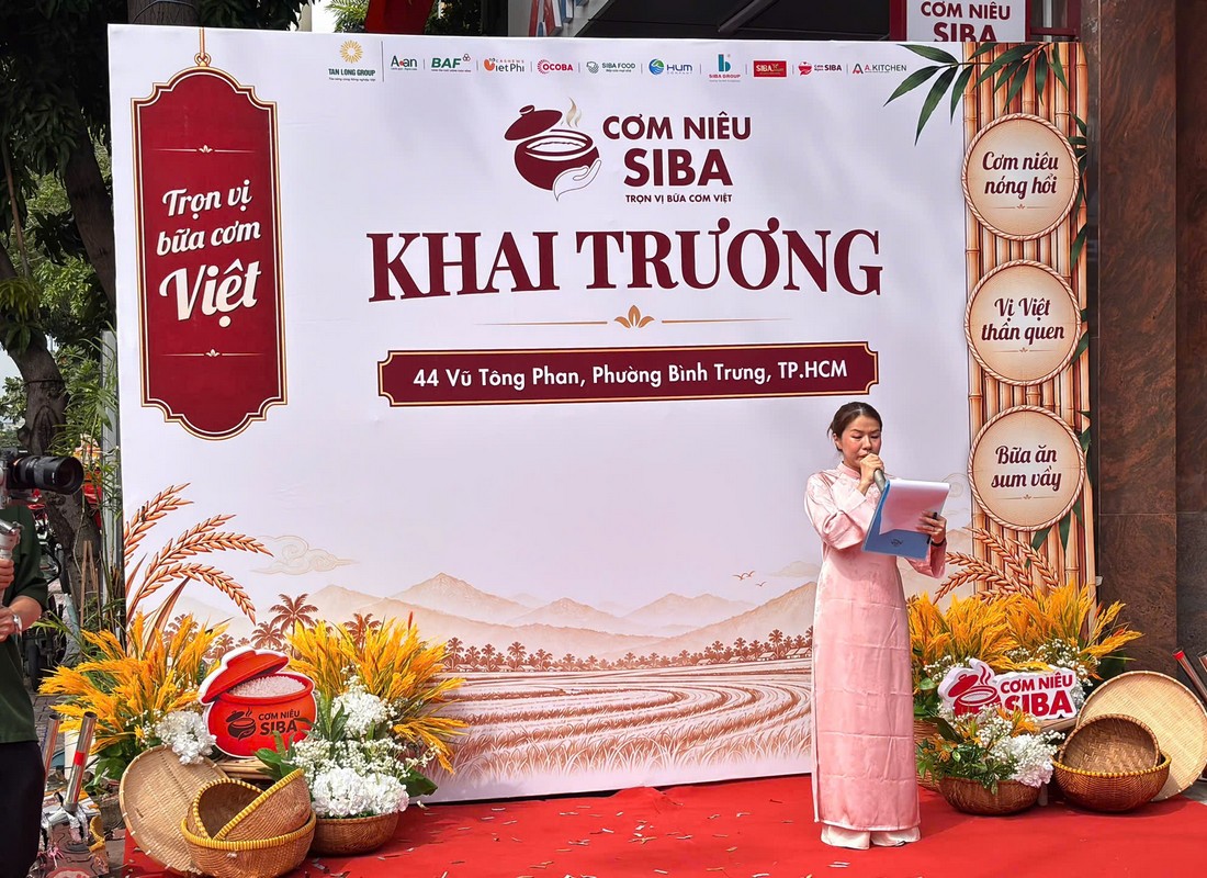 Nữ MC mặc áo dài hồng dẫn chương trình khai trương Cơm Niêu SIBA.